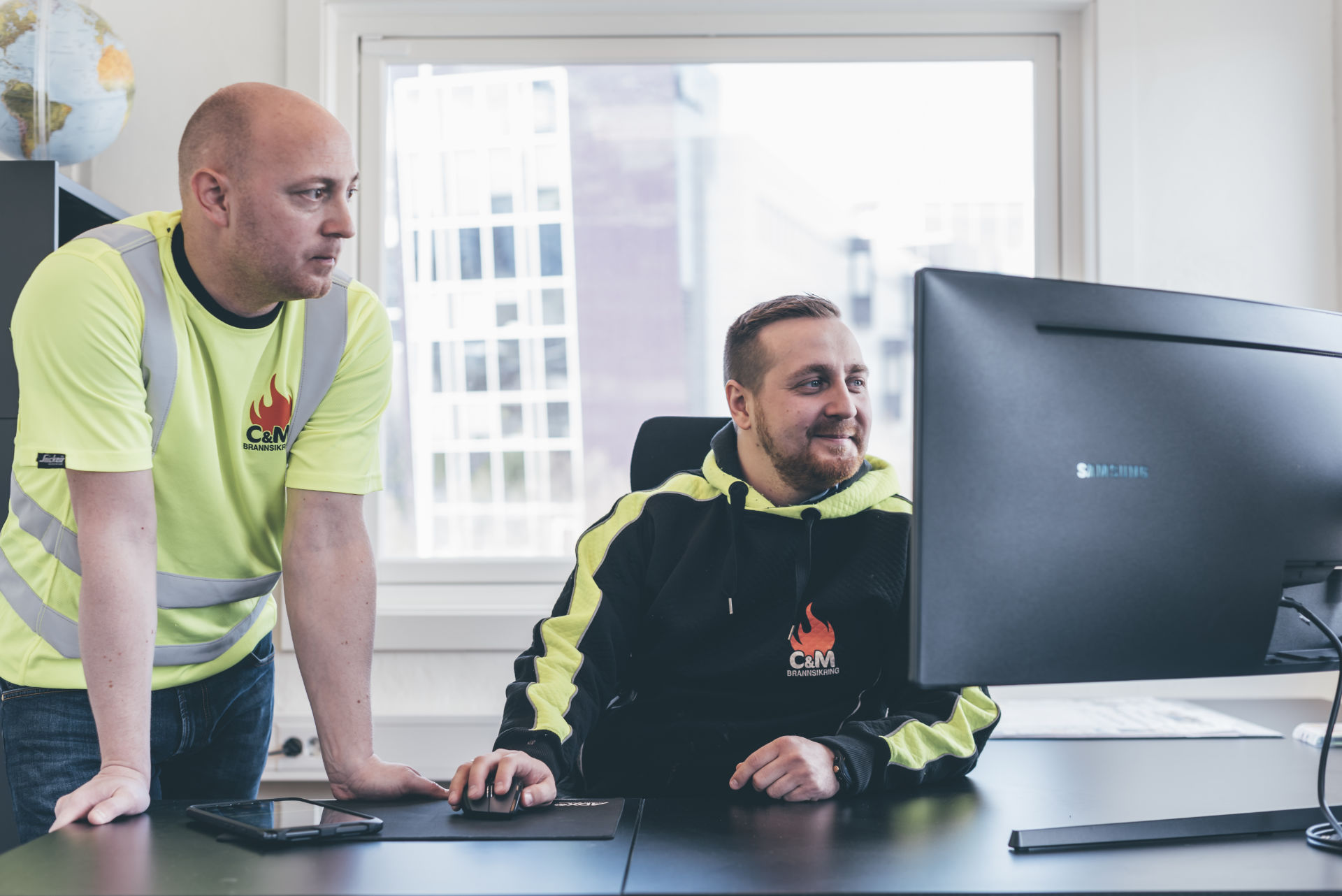 Christer og Michael, står ved datamaskin på kontoret Christer og Michael, står ved datamaskin på kontoret